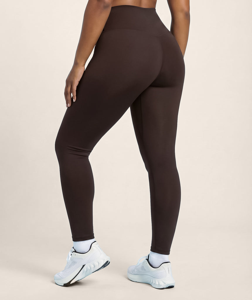 Person wearing coffee brown leggings on a beige background