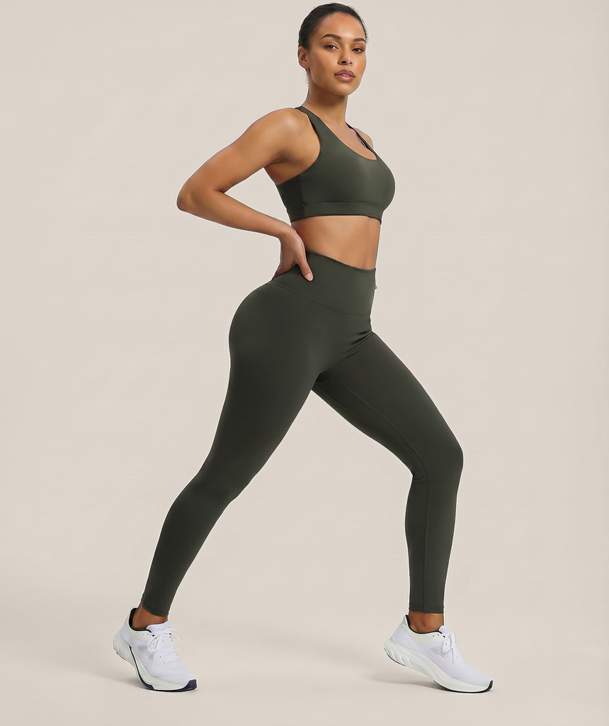 Woman wearing a green sports bra and leggings set on a beige background