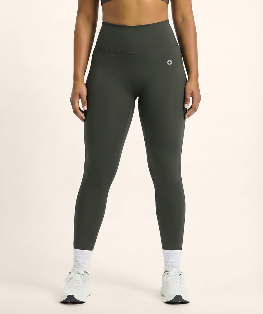 Person wearing dark gray leggings on a beige background