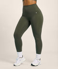 Person wearing olive green leggings on a beige background