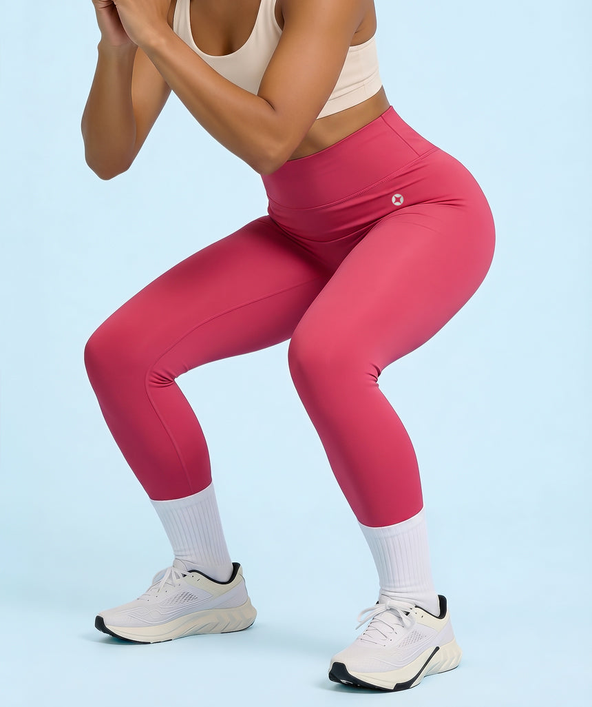 Model wearing raspberry red leggings and white sneakers on a light blue background