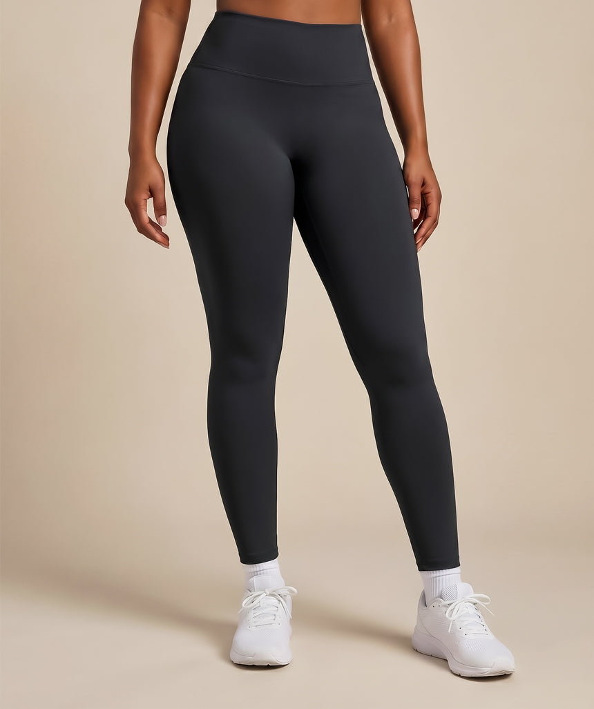 Person wearing black leggings and white sneakers on a beige background